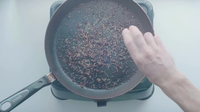 White Man's Hand Puts Cumin on a Black Frying Pan 