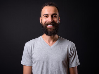 Young handsome Persian man with dreadlocks against black background