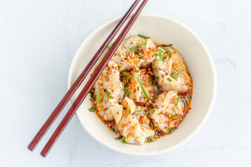 Chicken Dumplings / Wonton in Spicy Sichuan Sauce in a Bowl with Chopsticks Top Down Flat Lay Photo