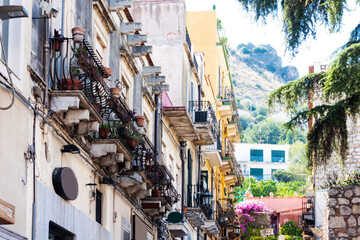 Traditional architecture of Sicily in Italy, typical street of Taormina, facade of old buildings .