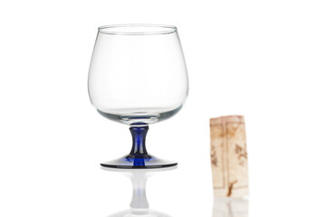 Wine glass close up and blurred wine cork on white background. Back focus