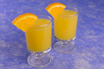 Vodka with orange juice in small glasses on a blue background.