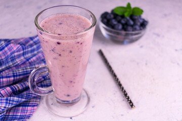 Blueberry and banana smoothie in a transparent glass on a white table.
View from above.