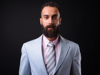 Young handsome Persian businessman with dreadlocks against black background
