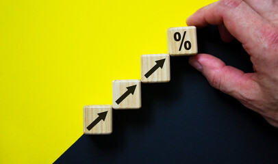 Business concept growth success process. Wood block stacking as step stair on paper yellow and black background, copy space. Male hand.