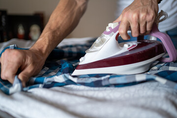 Guy ironing his shirt with an iron hands with iron