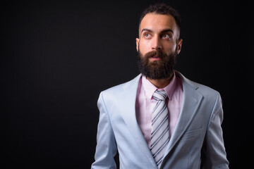 Young handsome Persian businessman with dreadlocks against black background