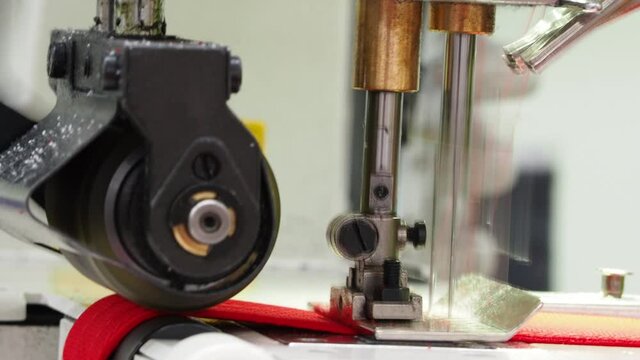 Close up of sewing process on the overlock in the garment factory. Tailoring industry..