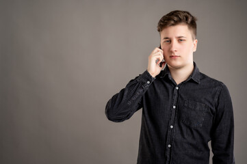 Portrait of serious stylish attractive man dressed with a casual black shirt talking on the phone