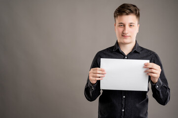 Portrait of serious stylish attractive man dressed with a casual black shirt holding white paper