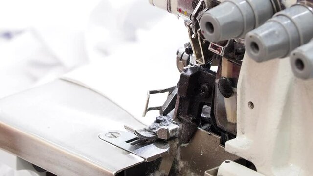 Close up of sewing process on the overlock in the garment factory. Tailoring industry..