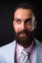 Young handsome Persian businessman with dreadlocks against black background