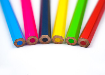Back side of six different colored wood pencil crayons on a white background