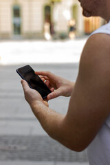 Image of man holding smartphone with blurred background.Close up young man holding mobile for checking work or make appointment and using application for manage job or surf the internet at outside.
