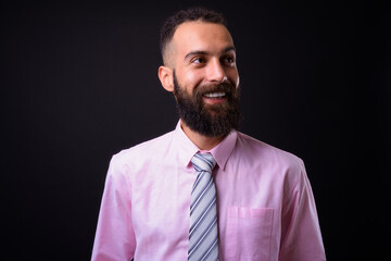 Young handsome Persian businessman with dreadlocks against black background