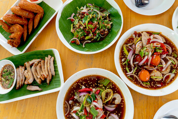 Top view  of Thai style foods. Yum : Fresh shrimp with spicy and sour sauce salad. Fried chicken. Roasted pork.