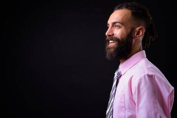 Young handsome Persian businessman with dreadlocks against black background