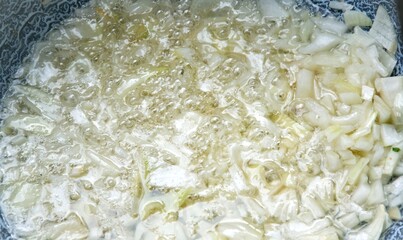 frying  onions  in big metal kettle in deep oil, extreme close up