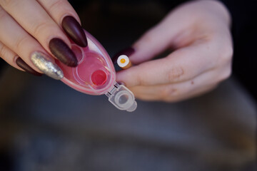 The girl's hands hold capsules for cigarettes and puts them into cigarettes. Banning flavored tobacco. The girl will buy, plozie habits, bypassing the rules.