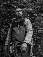 Viking warrior portrait with thick beard in front of a stone wall