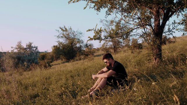 Large frame of a young tourist sitting on the grass for a short stop. It has a rug and a retro camera.