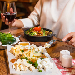 Woman eating tasty meat meal on the wooden plate with red wine