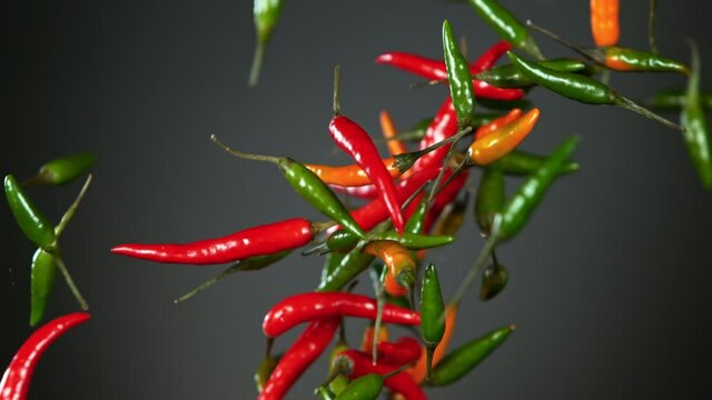 Super Slow Motion Shot of Mixed Chilli Side Colision on Dark Grey Background at 1000fps.