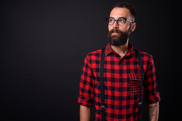 Young handsome Persian man with dreadlocks against black background