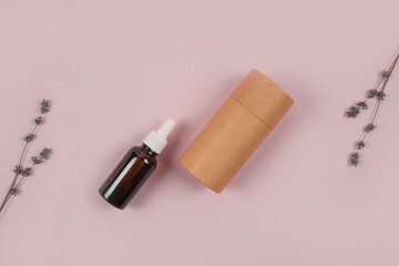 Dropper bottle with lavender essential oil and paper packaging tube with lavender flowers around on lilac background with copyspace for text. Mockup