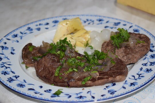 Roast beef heart with parsley and onions, served in a white and blue dish