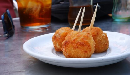 Plato de croquetas de jamón en una terraza con te helado