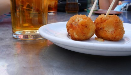 Plato de croquetas de jamón en una terraza con te helado