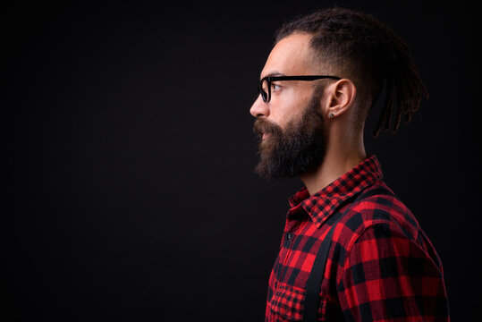 Young handsome Persian man with dreadlocks against black background