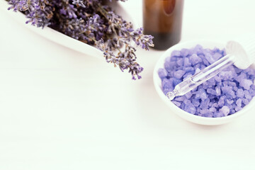Obraz na płótnie Canvas Dropper bottle with lavender essential oil and salt with lavender extract, lavender flowers as background with copyspace for text. Trendy toned photo for your blog or presentation