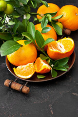 Ripe juicy tangerine, orange mandarins with fresh leaves on dark background