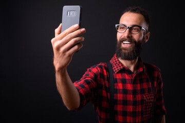 Young handsome Persian man with dreadlocks against black background