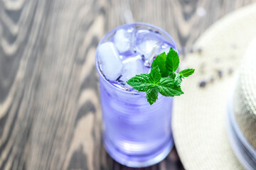 Lavender lemonade and ice cubes on a wooden table. Summer drink, iced tea.