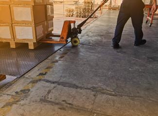 Worker driving forklift loading and unloading shipment carton boxes and goods on wooden pallet from container truck to warehouse cargo storage in logistics and transportation industrial 