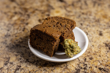 Cannabis infused brownies and single cannabis bud on white plate