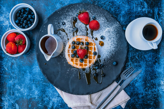 Delicious Waffles with strawberries and blueberries and a touch of honey with coffee on the side.