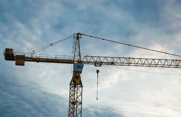 Yellow crane against the background of the blue sky with beautiful clouds. Lifting crane working. Big crane close up