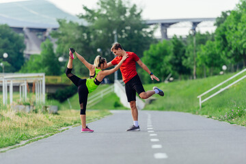 Young couple  warming up and stretching together in a park before running