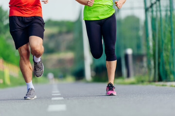 Close up feet with running shoes and strong athletic male and female legs jogging on the running track