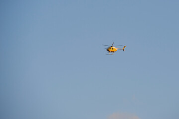 Flying small helicopter high in a blue cloudy sky.