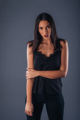 Sensual studio portrait of a sexy woman standing with one arm crossed on a gray background