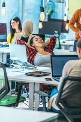 Obraz premium A young worker having a break and resting after solving a task while being surrounded by her colleagues. .