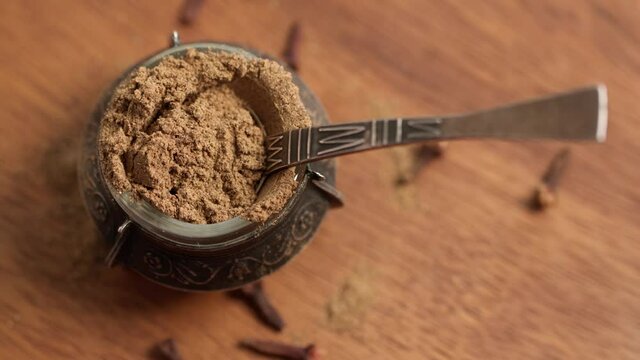 Cloves powder in vintage bowl with spoon rotate