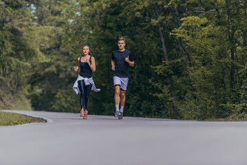 Athletic couple running on a street next to each other. Nature,fit and healthy concept.