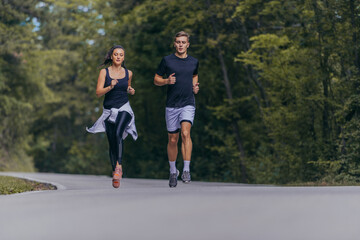 Athletic couple running on a street next to each other. Nature,fit and healthy concept.