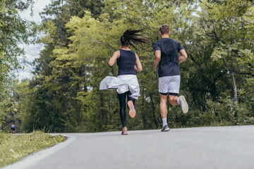 Young fit couple atheltes running on running road in a forest.